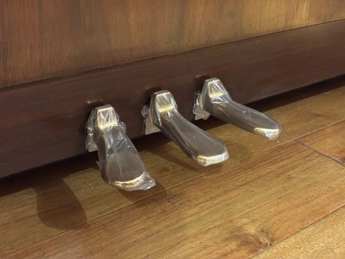 Three brass pedals on a walnut upright piano